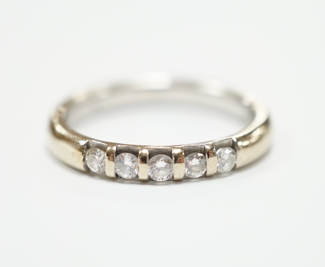 A modern 18ct white gold and five stone diamond set half hoop ring, size J, gross weight 3.6 grams.